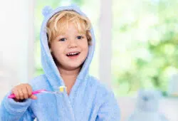 An Adorable Little Boy Iin A Baby Blue Robe Brushing His Teeth